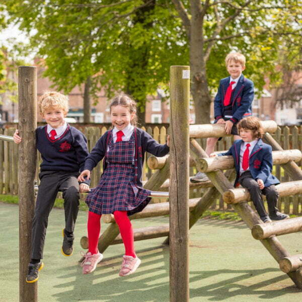 Four pupils are sat on the climbing equipment in the Junior School playground.