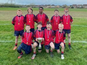 Nine pupils are stood together holding a trophy and they are wearing medals.